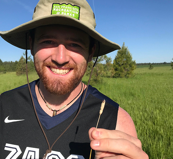 A woman stands next to several kayaks