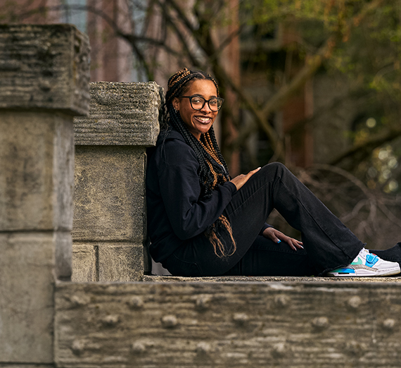A main with a mustache wearing a brown t-shirt and necklace